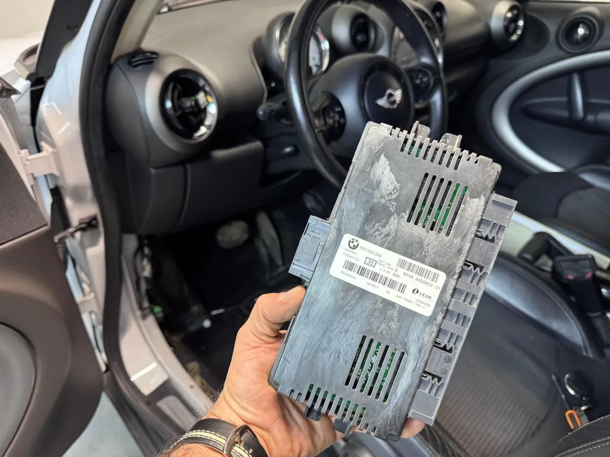 Modulo luci FRM3 BMW MINI smontato e tenuto in mano davanti all'abitacolo
